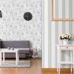 Stylish living room with grey sofa and small coffee table. Light interior with flooring and decorative wallpaper.